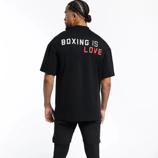 Person wearing a black t-shirt with 'Boxing is Love' text on the back against a white background